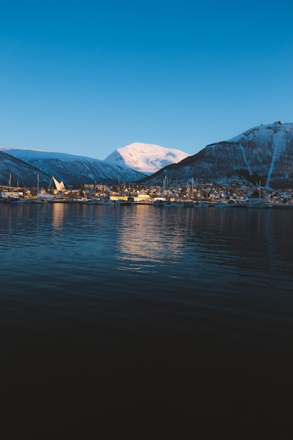 Вертикальный снимок озера в окружении заснеженных гор в Тромсё, Норвегия