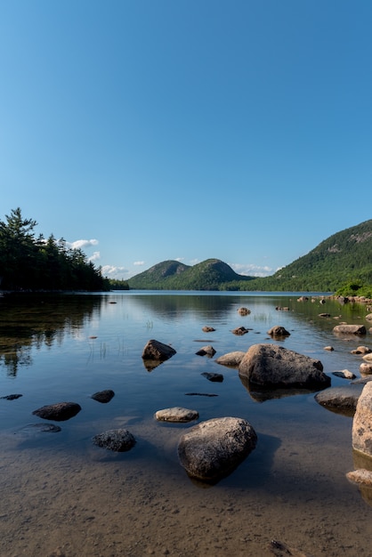 Vertical shot of a lake with big stones and the reflection of the sky in it