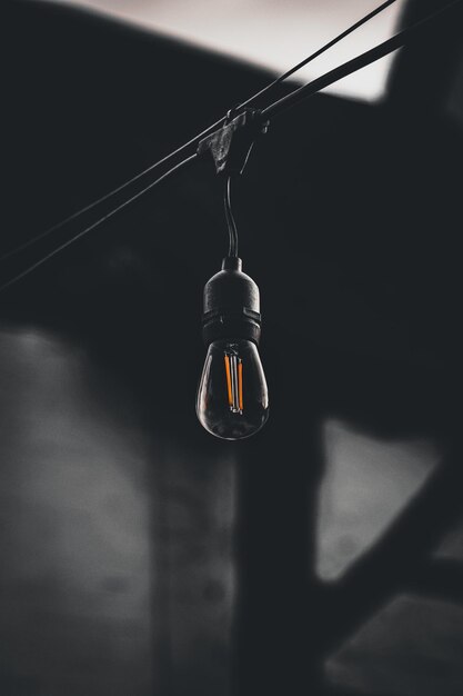 Vertical shot of a lamp hanging on a wire on a dark blurry background