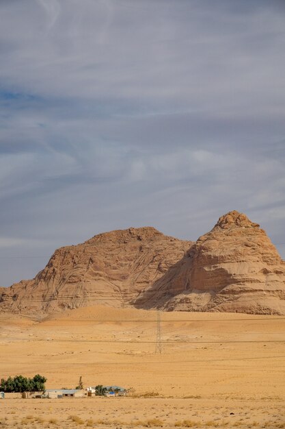 Vertical shot of a large cliff on a desert under a cloudy sky