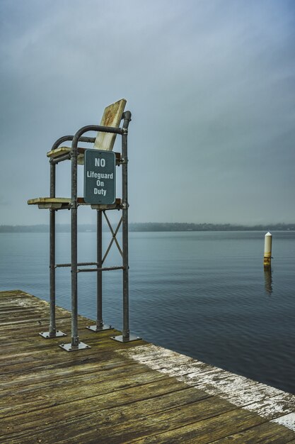 Vertical shot of a lifeguard station in the dock with an open sea and a gloomy sky in the background