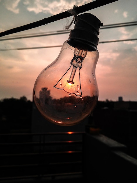 Foto gratuita colpo verticale di una lampadina contro il cielo al tramonto