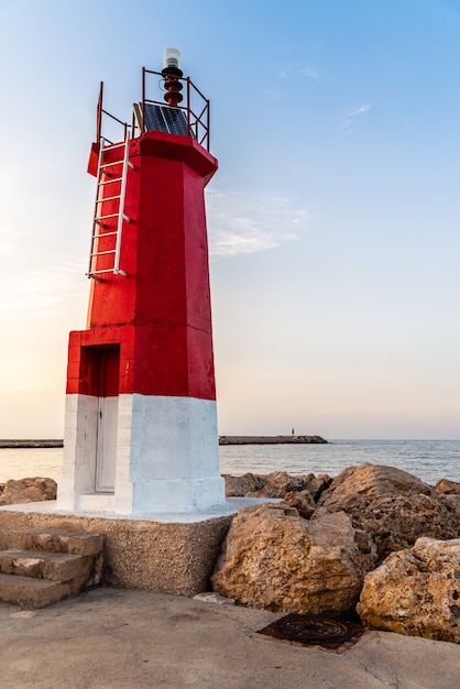 Vertical shot of a lighthouse near the sea under a blue sky