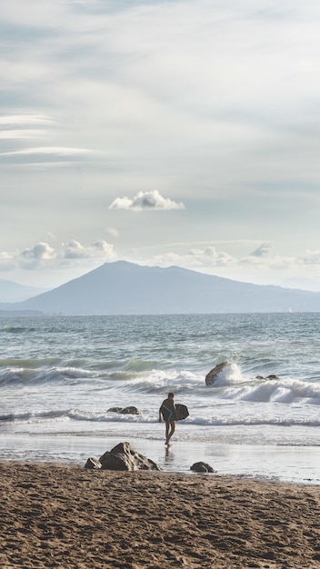 Vertical shot of a lonely surfer on a sea