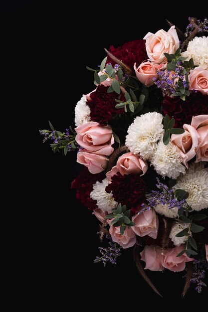 Вертикальный снимок роскошного букета розовых и красных роз и белых георгинов на черном фоне