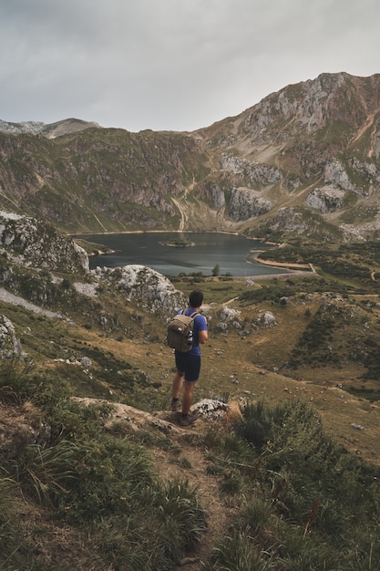 スペインのソミエド自然公園の美しい湖を見ている男性のバックパッカーの垂直ショット