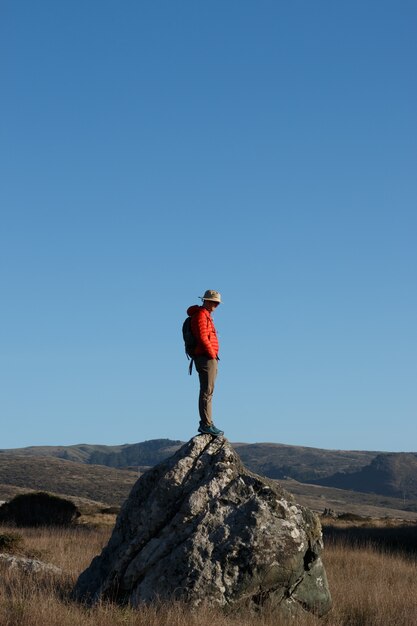 山の石の上に立っている男性ハイカーの垂直ショット