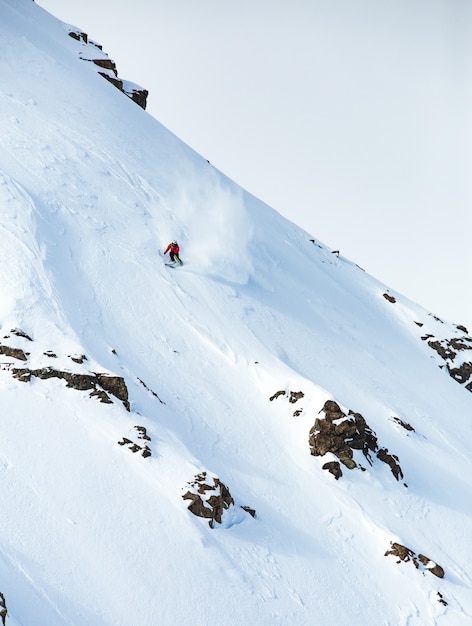 冬に雪で覆われた山でスキーをする男性の垂直ショット