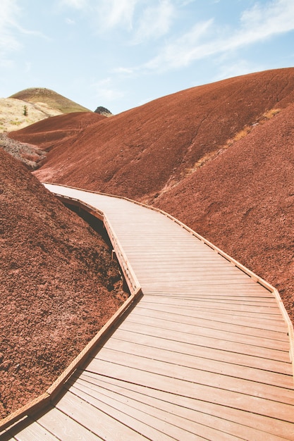 Vertical shot of a man-made wooden road in the hills of red sand