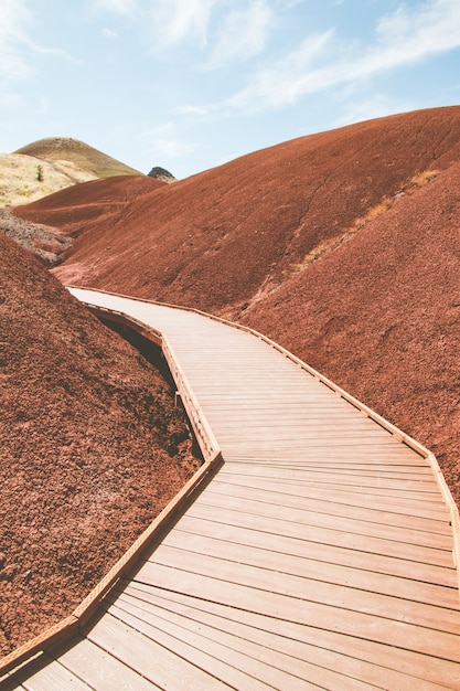 Foto gratuita colpo verticale di una strada in legno artificiale nelle colline di sabbia rossa