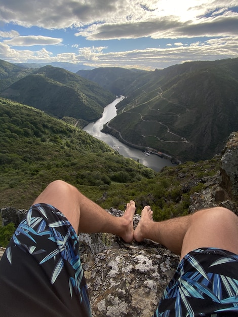 Vertical shot of a man sitting on a stone in the Sil Canyon in Spain