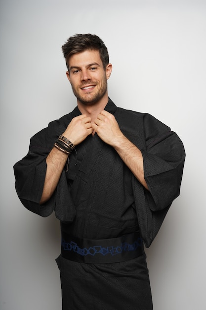 Вертикальный снимок мужчины в кимоно в японском стиле и улыбающегося