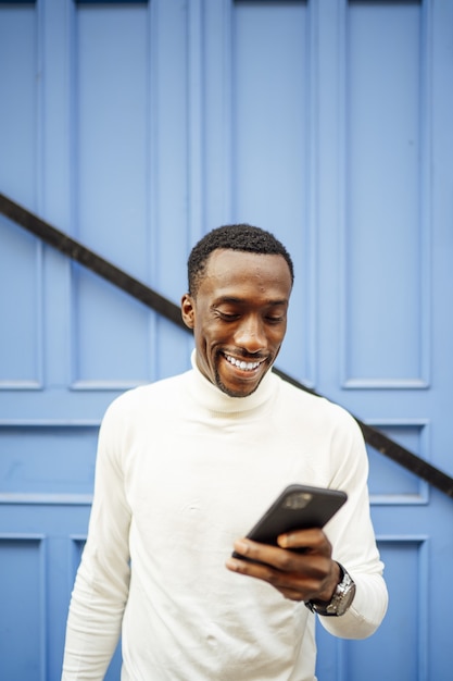 Free photo vertical shot of a man wearing a turtleneck looking at his phone