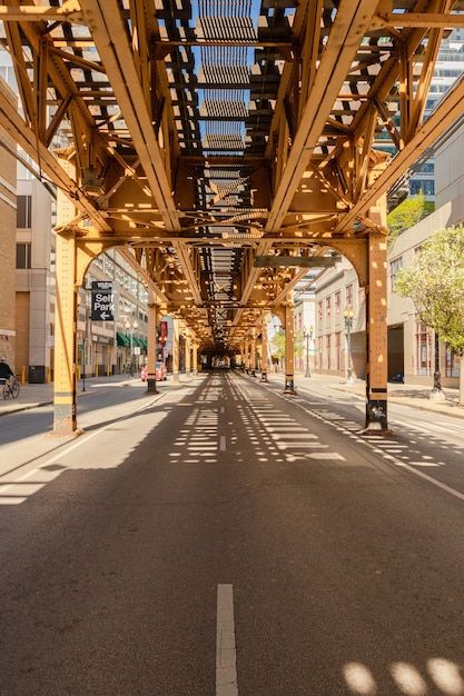 Vertical shot of the monorail bridge above a street captured on a sunny day in Chicago