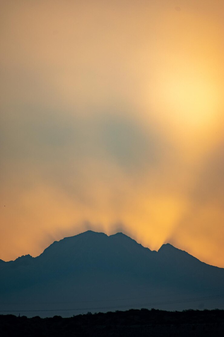 무료 Photo 해가 지는 하늘을 배경으로 산의 실루을 수직으로 찍은 사진