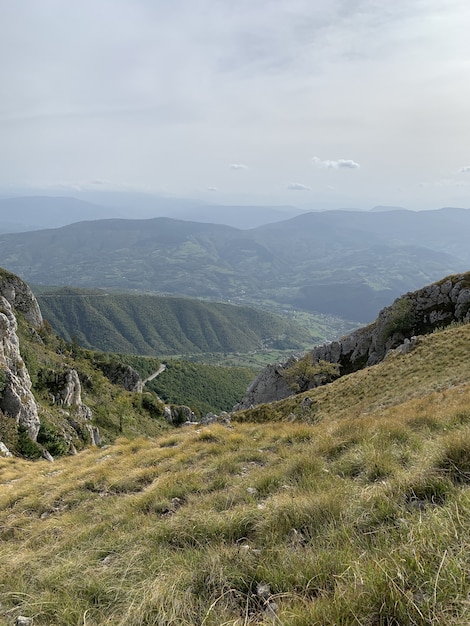 Vertical shot of mountains covered in greenery under a cloudy sky