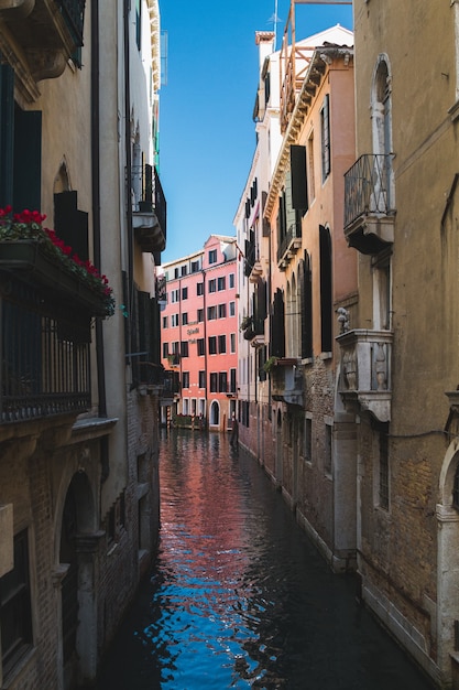 イタリア、ベニスの建物の真ん中にある狭い運河の垂直方向のショット