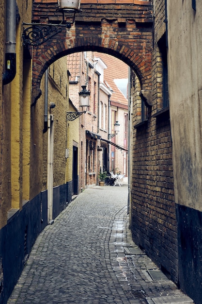 Vertical shot of the narrow streets of the Bruges in Belgium with old brick walls