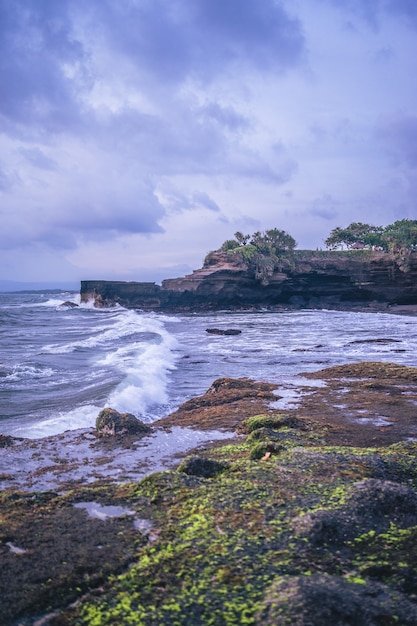 Vertical shot of an ocean shore with cliffs on a cloudy day