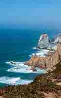 Free photo vertical shot of an ocean with cliffs and rocks on the shore