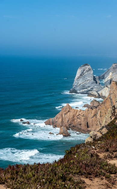 Vertical shot of an ocean with cliffs and rocks on the shore