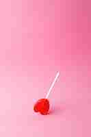 Бесплатное фото Вертикальный снимок леденца на палочке в форме сердца на розовом фоне