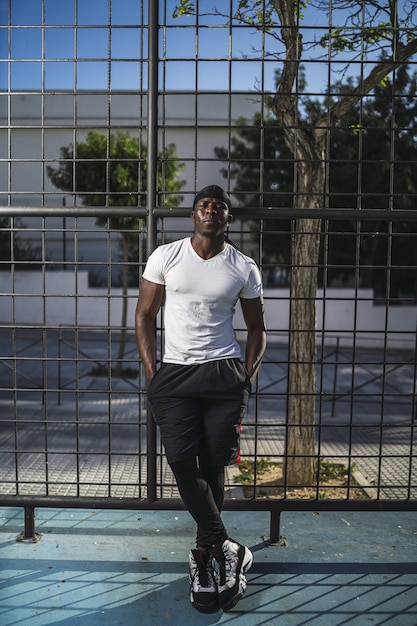 無料写真 フェンスに寄りかかって白いシャツを着たアフリカ系アメリカ人男性の垂直ショット