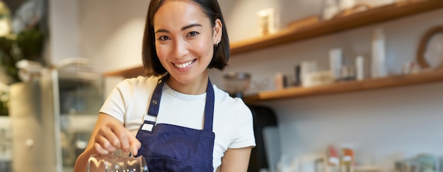 無料写真 笑顔の可愛いバリスタの女の子がフィルターコーヒーを注ぎ ⁇ カフェのクライアントのために注文をしている垂直ショット