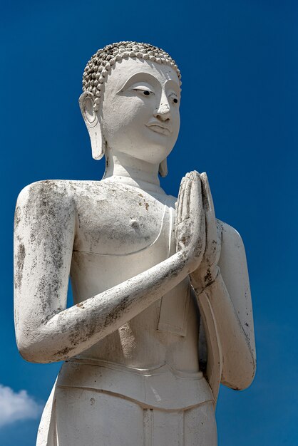 Vertical shot of an old Buddha statue with a clear blue sky