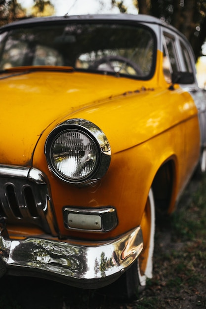 Vertical shot of an old yellow vintage car