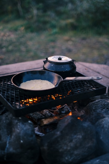 Free photo vertical shot of a pan and kettle on the grill