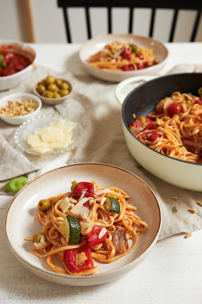 Vertical shot of pasta with vegetables and ingredients on a white table