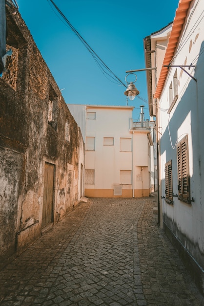 Vertical shot of a pathway in the middle of white buildings under a blue sky