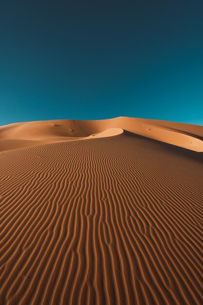 Vertical shot of a peaceful desert under the clear blue sky captured in Morocco