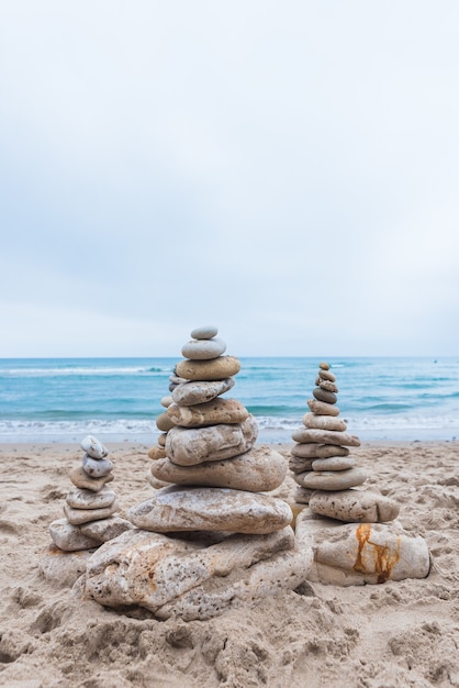 Foto gratuita colpo verticale di ciottoli impilati l'uno sull'altro in equilibrio sulla spiaggia