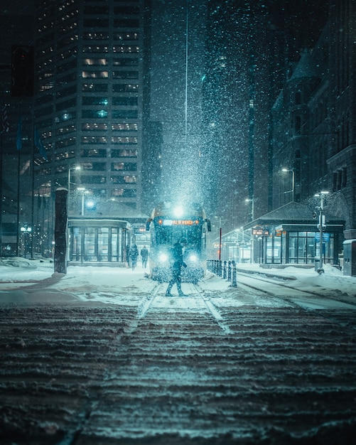 Vertical shot of a person in front of a train on a snowy road