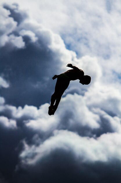 空をぼやけて空中ジャンプする人の垂直ショット