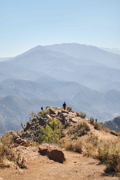 Вертикальный снимок человека, идущего на расстоянии от края горы