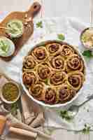 Free photo vertical shot of pesto pizza rolls with pine nuts and herbs butter on a white table