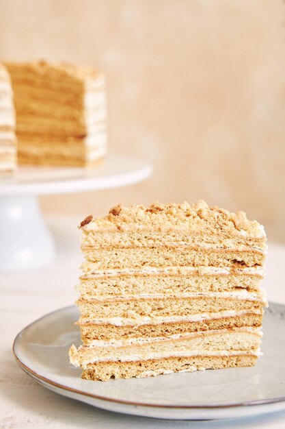 Vertical shot of a piece of a delicious layered cake with cream and a crumb topping on the table