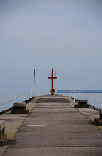 Vertical shot of a pier leading to the ocean under the clear sky