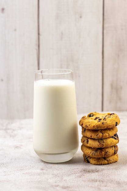 Vertical shot of a pile of chocolate chip cookie beside a glass of milk on a table