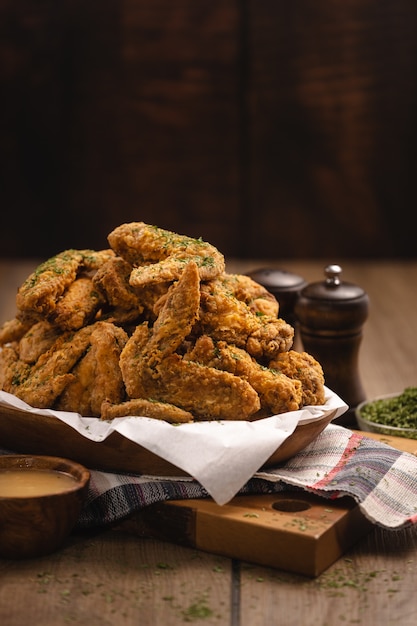 Foto gratuita colpo verticale di un mucchio di ali di pollo fritte e alcune spezie su un tavolo di legno