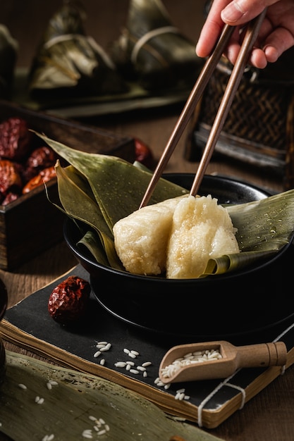 Vertical shot of preparation of rice dumplings with banana leaves