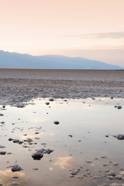 夕日を映し出す岩だらけの水たまりの縦ショット