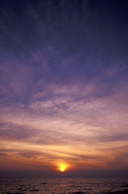 夕暮れ時の海の上の紫と黄色の空の垂直ショット