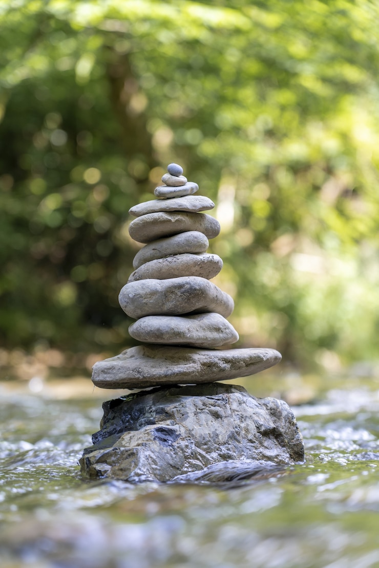 Free Photo vertical shot of a pyramid of stones balanced on a river water