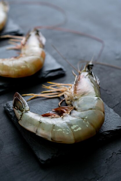 Vertical shot of raw shrimps on black rock slates