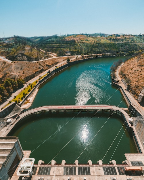 Foto gratuita colpo verticale di un fiume vicino alle strade della città sotto un cielo blu chiaro