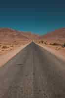 Foto gratuita colpo verticale di una strada in mezzo al deserto e montagne catturate in marocco